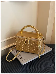 Gold metallic studded vanity box bag detail showcasing top handle and chain strap design.
