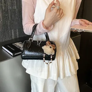 Chic black patent leather boston pillow bag with cute plush bear charm for daily commuting.