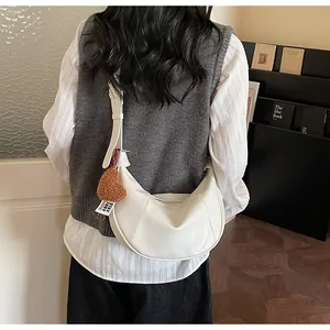 White minimalist hobo dumpling shoulder bag with plush heart charm and adjustable strap.