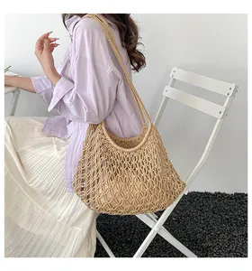 Hand-woven beige hollow mesh tote bag with inner pouch worn by a model in a studio