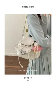 Close-up of a sweet creamy white backpack with silver bow detail worn by a model