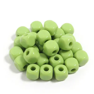 Primer plano de cuentas cúbicas de acrílico verde claro, textura brillante para joyería DIY.