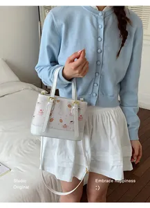 Close-up of white crossbody bucket bag with cute dessert pattern and top handles
