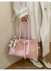Elegante rosa geflochtene Tragetasche mit Gürteldetail, gehalten von einem Model