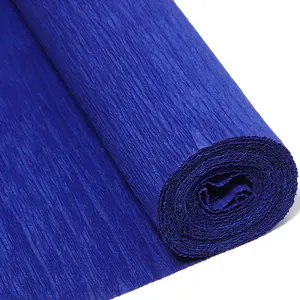 Primer plano de rollo de papel crepé azul oscuro mostrando finas texturas arrugadas para manualidades.