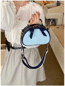 Detailansicht einer stilvollen blauen Jeans Umhängetasche mit Schleife und goldenem Design.