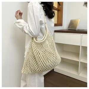 Primer plano de un bolso tote de macramé crema con un diseño calado muy intrincato.