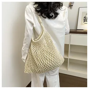 Modelo con un bolso tote de punto calado crema en un ambiente interior minimalista