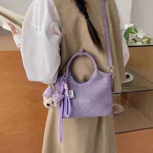 Detailansicht der stylischen lila Beuteltasche mit süßem kariertem Bären-Anhänger.