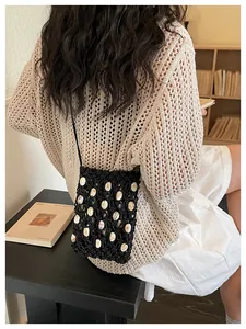 Detalle de bolso bandolera tejido negro con adornos de conchas para el verano