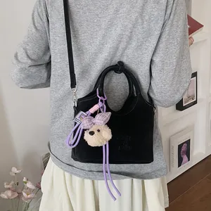 Detailansicht der stilvollen schwarzen minimalistischen Beuteltasche mit süßem Plüschhund-Anhänger.