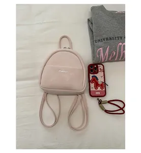 Detail view of a minimalist pink mini backpack with cute straps and clean front pocket design.