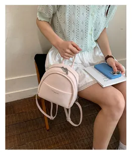 Details of the mini pink leather backpack featuring a front pocket and comfortable shoulder straps.