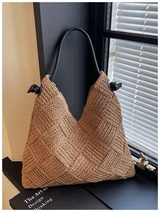 Grand sac fourre-tout en paille tissée avec poignée noire dans un cadre élégant et spacieux.
