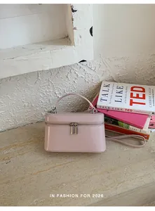 Elegante roze box handtas met handvat en verstelbare schouderriem op een stenen tafel