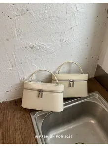 Elegante crèmekleurige boxhandtassen met dubbele zilveren ritsen in een lifestyle-omgeving