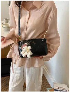 Stylish black quilted patent leather shoulder bag with cute bear keychain for women.