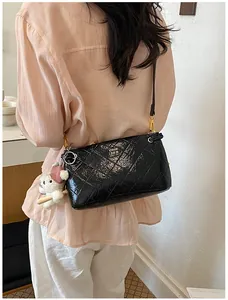 Close-up detail of the black quilted leather shoulder bag with chic hardware and cute bear pendant.