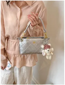 Silver quilted underarm bag detail with metallic texture and cute bear charm accessory.