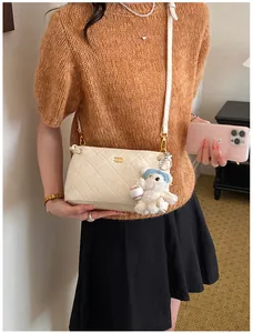 Detailed shot of the white quilted underarm shoulder bag featuring chic chain strap and cute pendant.