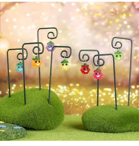 Gros plan de lutins de fruits en résine colorée sur des tiges en fil de fer vert décor.