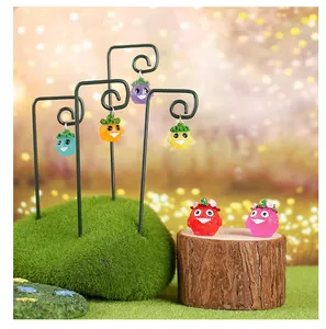 Figurines d'elfes en résine suspendues sur des tiges métalliques dans un décor de jardin.