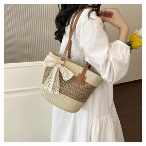 Chic women's straw woven shoulder bag featuring brown handles and elegant lace bow detail.