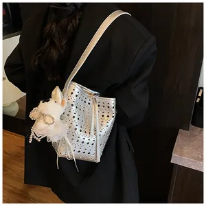 Detailansicht einer silbernen Lochmuster-Eimertasche, getragen über einem schwarzen Blazer