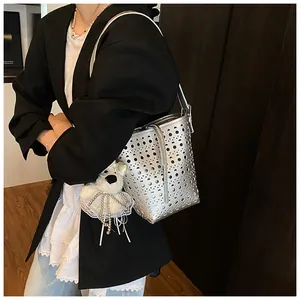 Nahaufnahme einer modischen silbernen Beuteltasche mit hübschem Plüschbären-Anhänger.