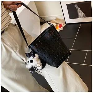 Detailansicht einer schwarzen, lasergeschnittenen Eimertasche mit süßem Hunde-Plüschanhänger