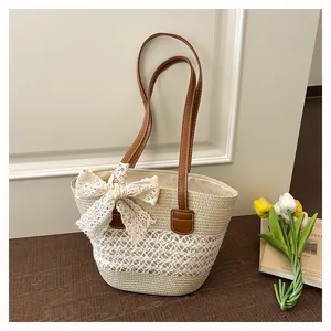 Detailed shot of a stylish straw woven tote bag with brown leather handles and a lace bow.