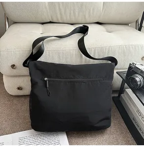 Detail view of the black messenger bag showcasing exterior zipper pocket and sturdy strap.