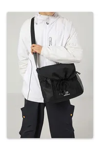 Detail view of the black utility messenger bag with drawstring closure and mesh side pockets.