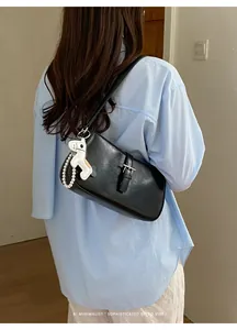 Vue détaillée du sac porté épaule rétro noir avec boucle métallique et pendentif perle.