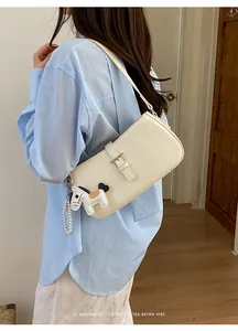 Vue rapprochée du sac à épaule blanc minimaliste avec charm de cheval et lanière perlée.