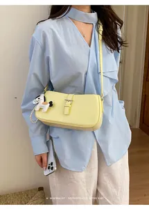 Vue detaillee d'un sac porte-epaule jaune avec breloque cheval en perle et bouclerie.