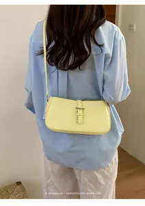 Détail de sac à épaule rétro jaune minimaliste montrant cuir lisse et bride à boucle.