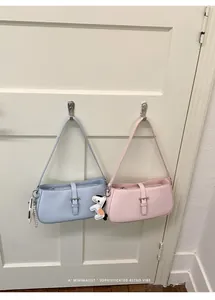 Détail de sac porté épaule pastel minimaliste avec boucle élégante et joli pendentif.