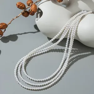 Gros plan d'un collier de perles d'eau douce blanches à plusieurs rangs sur un vase