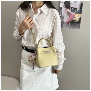 Modelo con un elegante bolso bombonera de cuero amarillo claro con detalle de cerradura