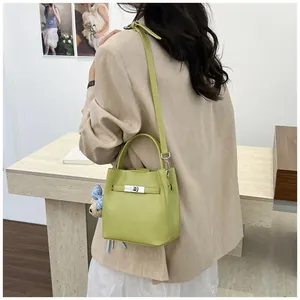 Primer plano de un bolso de cubo verde lima llevado por una modelo con blazer