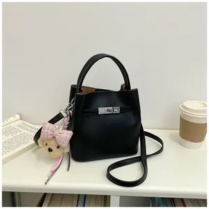 Elegante bolso bombonera de cuero negro con dije de oso en un entorno de estilo de vida