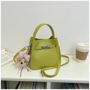 Vista detallada de un elegante bolso cubo verde lima con colgante de oso de peluche