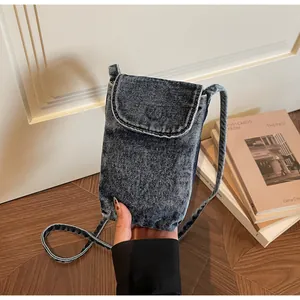 Close-up of the vintage denim crossbody phone bag detail, showing washed fabric and shoulder strap.