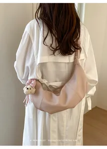 Elegant minimalist cream dumpling underarm bag with a plush puppy charm on model