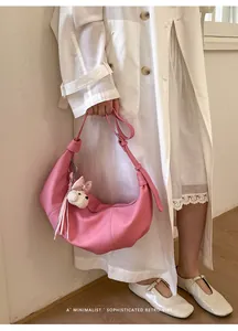 Pink dumpling shoulder bag shown with a cute white dog plush charm on a model