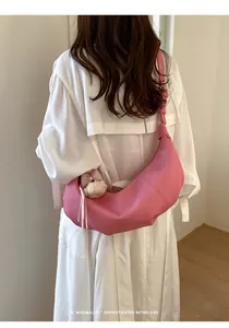 Stylish minimalist pink dumpling hobo bag worn crossbody with cute bear plush charm