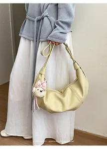 Minimalist beige crescent dumpling shoulder bag featuring a cute teddy bear pendant charm