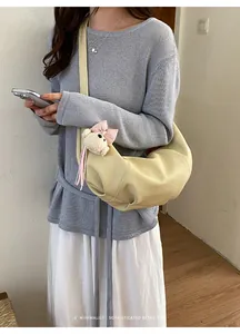 Stylish yellow croissant shoulder bag with cute bear pendant, perfect for daily commuting.