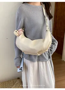 Minimalist croissant shoulder bag for women, chic hobo crossbody purse with cute bear charm.